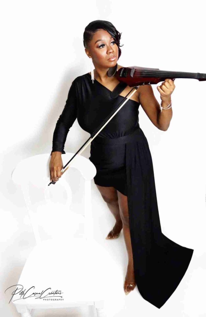 Woman playing violin in elegant black dress.