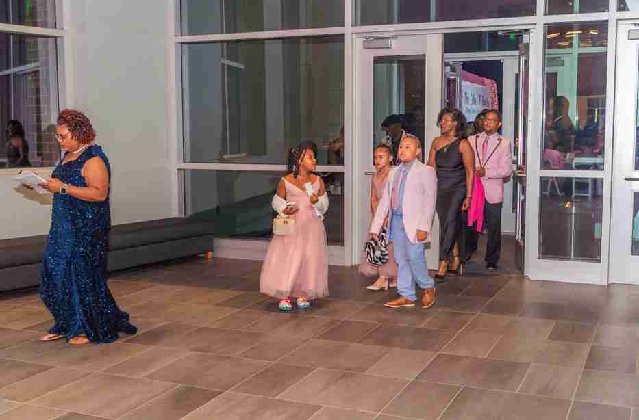 Children dressed up, walking indoors at an event.