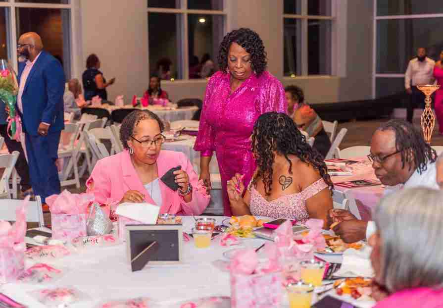 Women enjoying a lively gathering with food and drinks indoors.