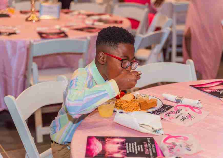 A young boy enjoying a meal at a formal event.