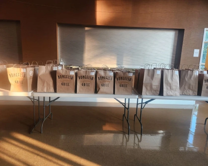 A row of brown paper bags on a table in a room with a metallic wall.