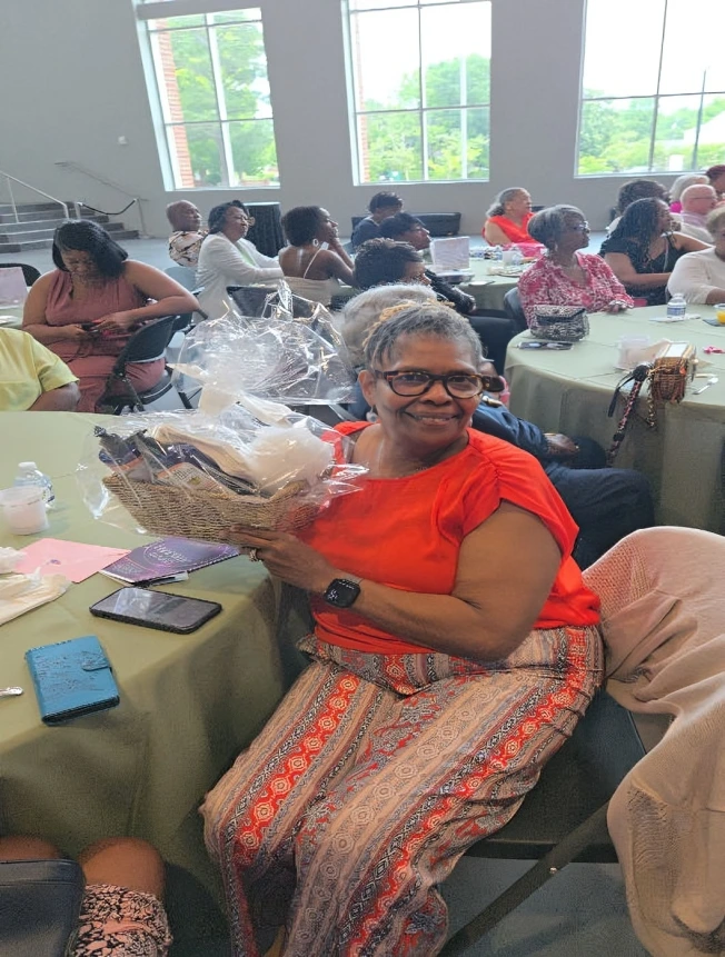 A joyful woman proudly holding a basket at a gathering.