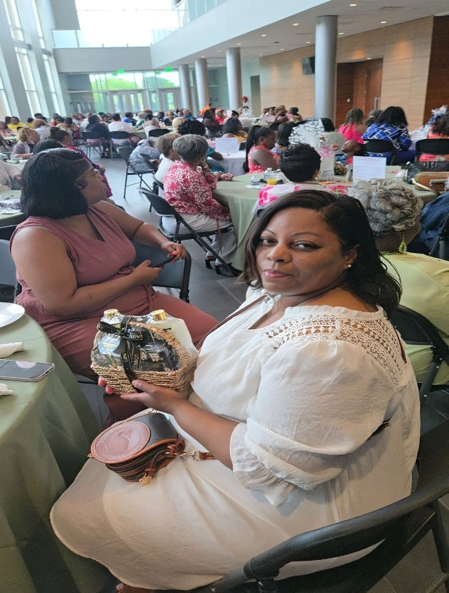 Two women sitting at a crowded event, one holding a smartphone.