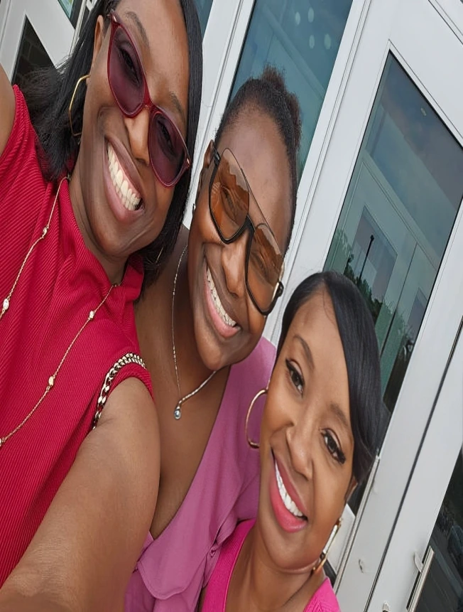 Three smiling women posing for a selfie outdoors.
