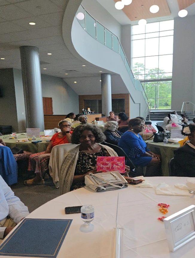 A group of people seated around tables in a bright indoor setting.
