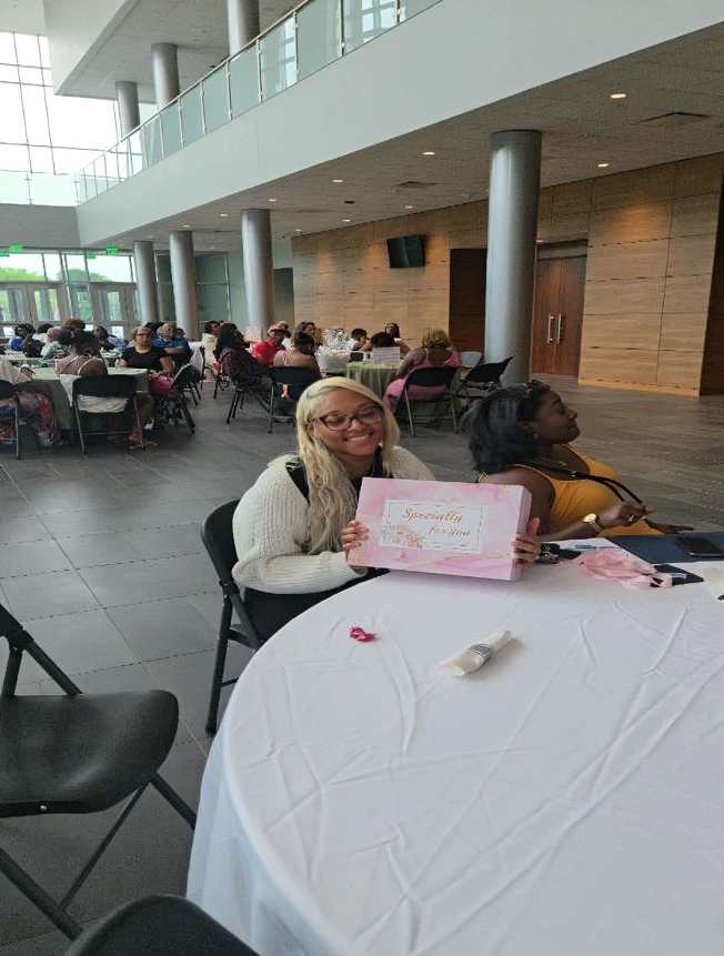 Two women sitting at a round table with a certificate in a spacious indoor area.