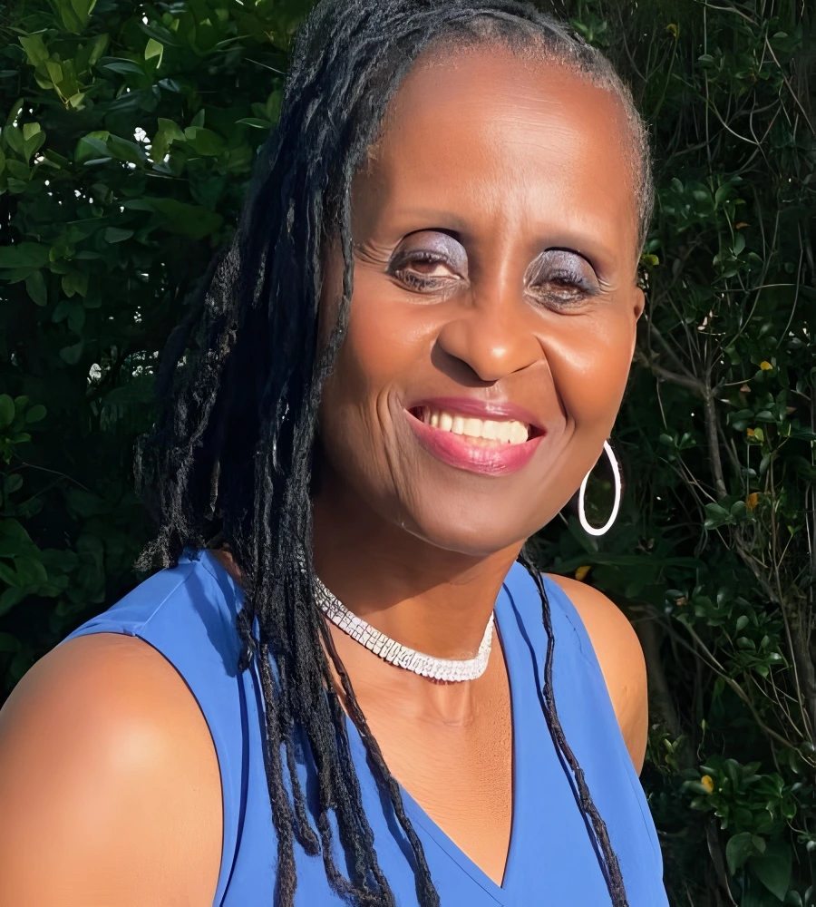 Woman with braided hair smiling outdoors in blue dress.